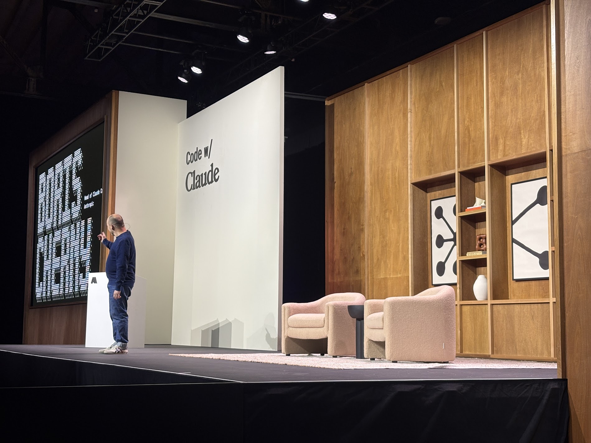 The Code w/ Claude main stage, with Boris Cherny presenting alongside a wood-paneled set and pink boucle armchairs
